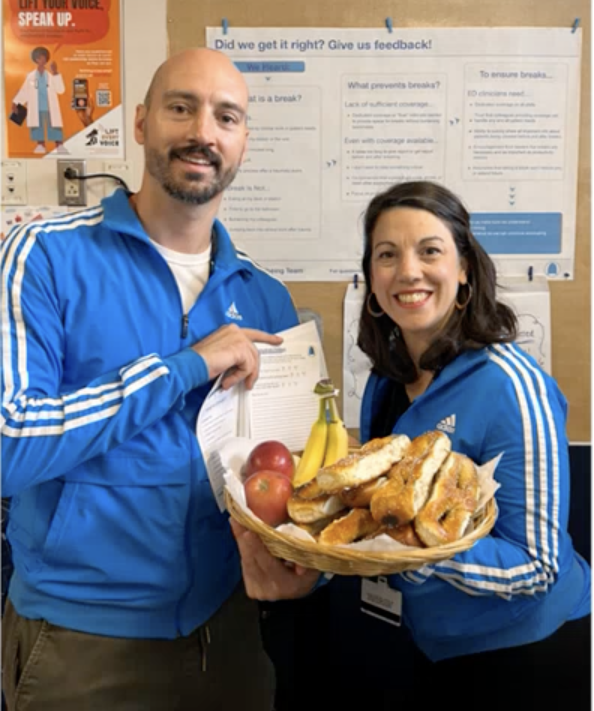 Ken and Brenna in blue jackets, holding a basket of food