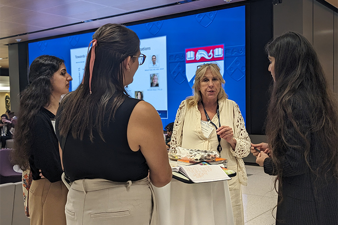 Krishleen speaks with a three women around a table during the Nudge symposium