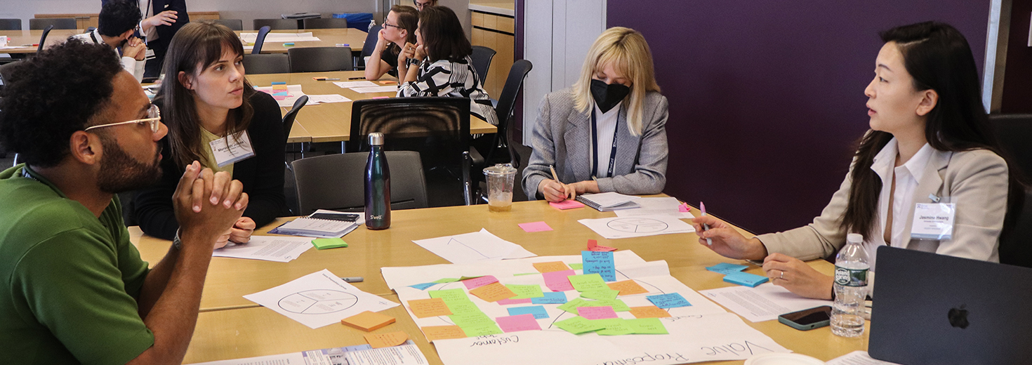 Workshop participants around a table which has on it poster paper covered in sticky notes