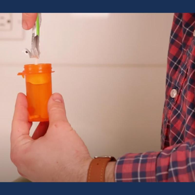 Person pouring opioid inactivating powder into pill bottle