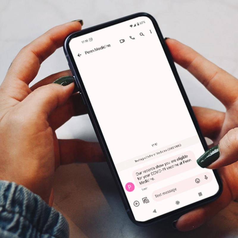 Hands holding a phone displaying text messages related to vaccine scheduling 