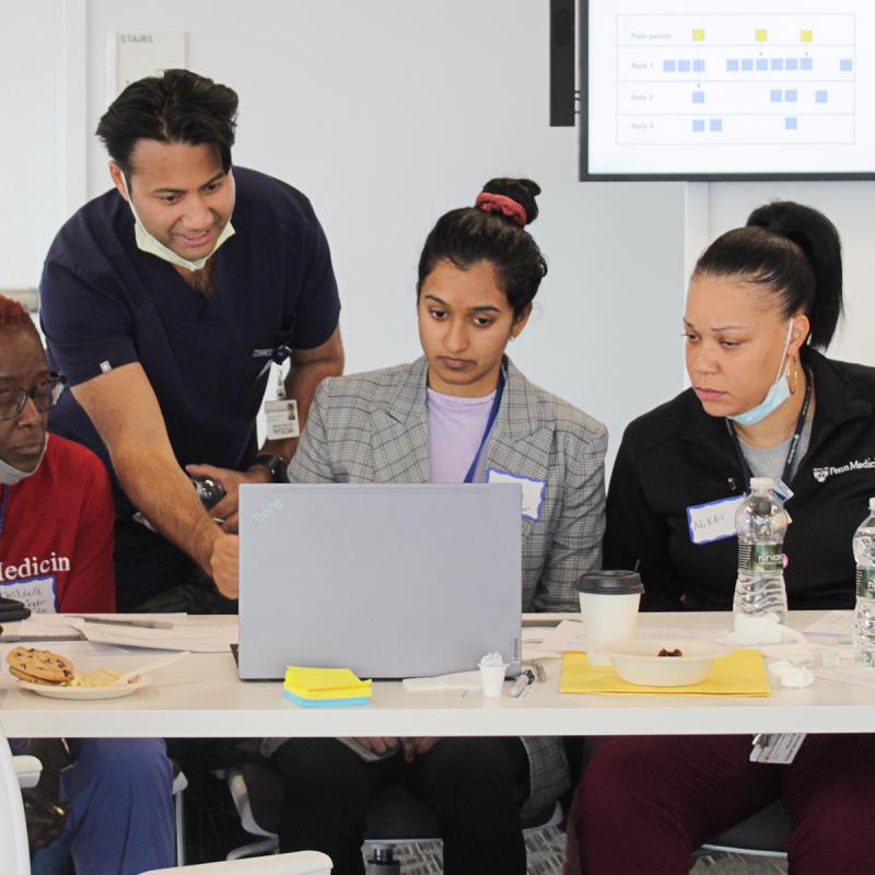 Members of the hackathon GI team look at a laptop together