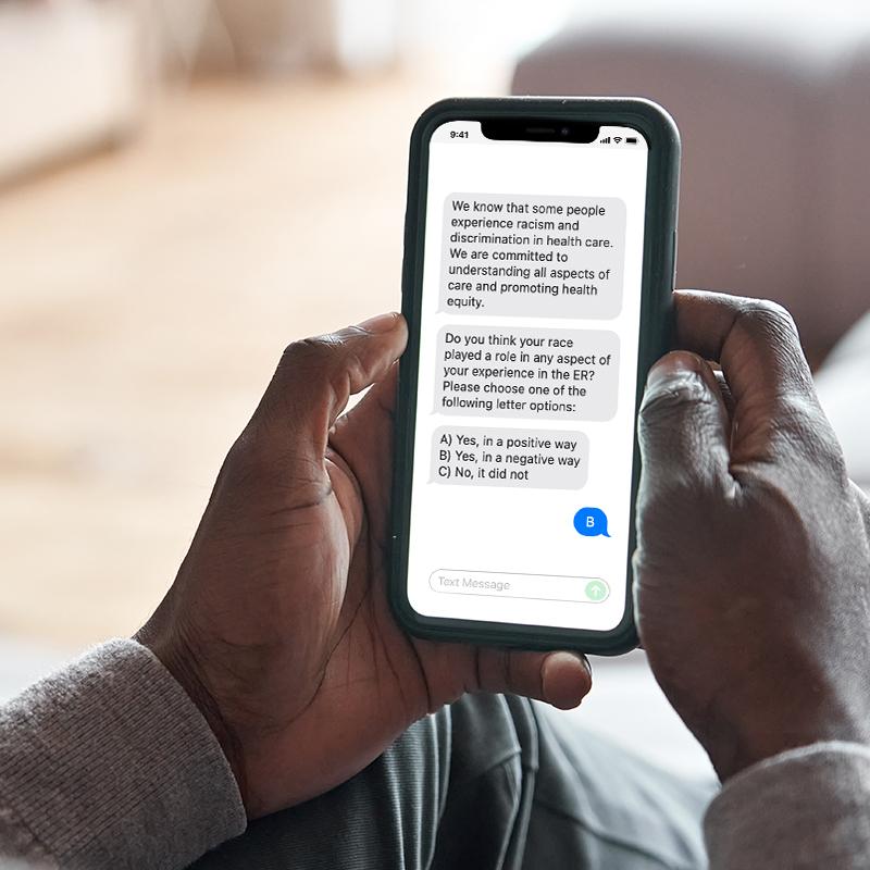 Person's hands holding a phone displaying text message question about experienced racism