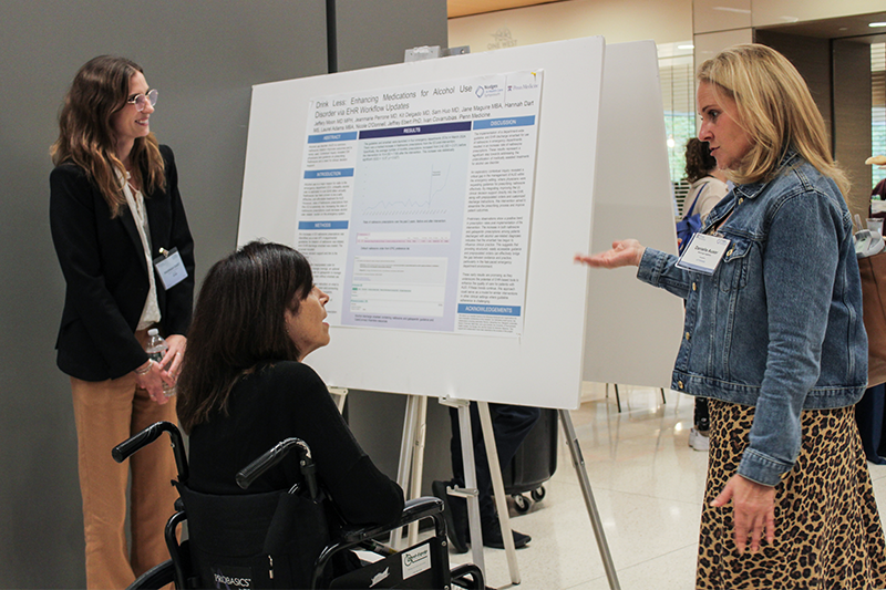 Three people talking in front of a research poster